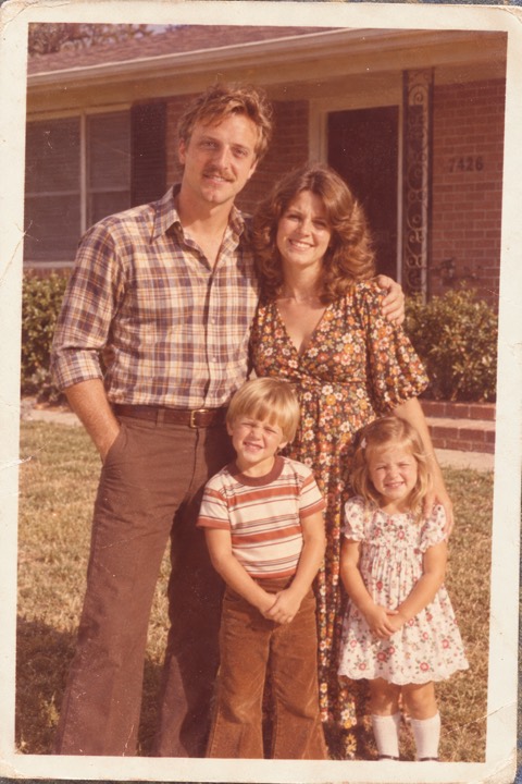 At thirty with his wife and two small children outside their house